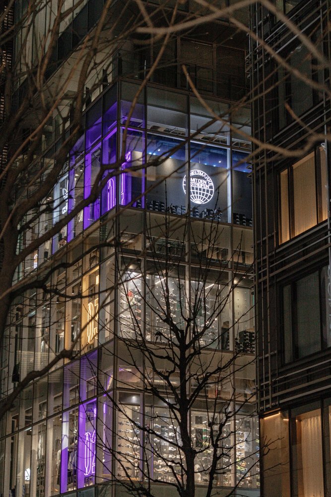 Multi-storey glass retail building lit with purple neon lights at night in Tokyo — Zen Den Studios