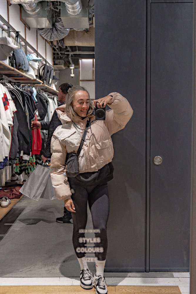 Liz with camera taking a mirror selfie inside a Tokyo streetwear store — Zen Den Studios