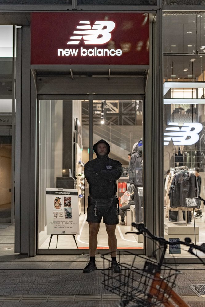 Hugh with arms crossed outside a New Balance store at night in Tokyo — Zen Den Studios